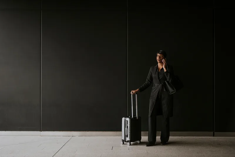 Business traveller with a suitcase taking a call in an airport terminal