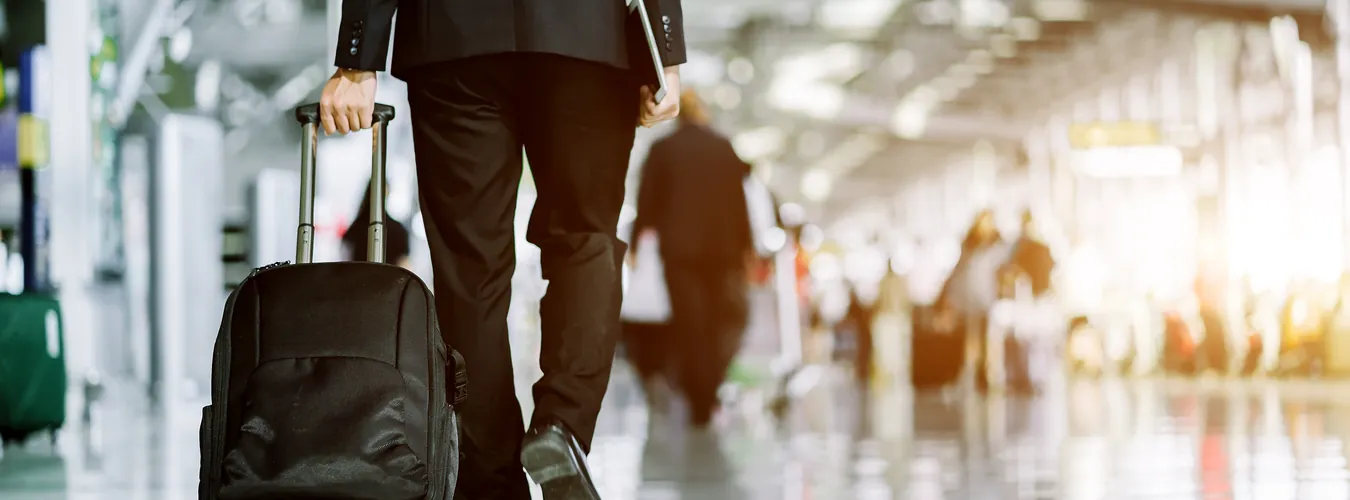 Businessman in a suit walking through an airport terminal with a suitcase