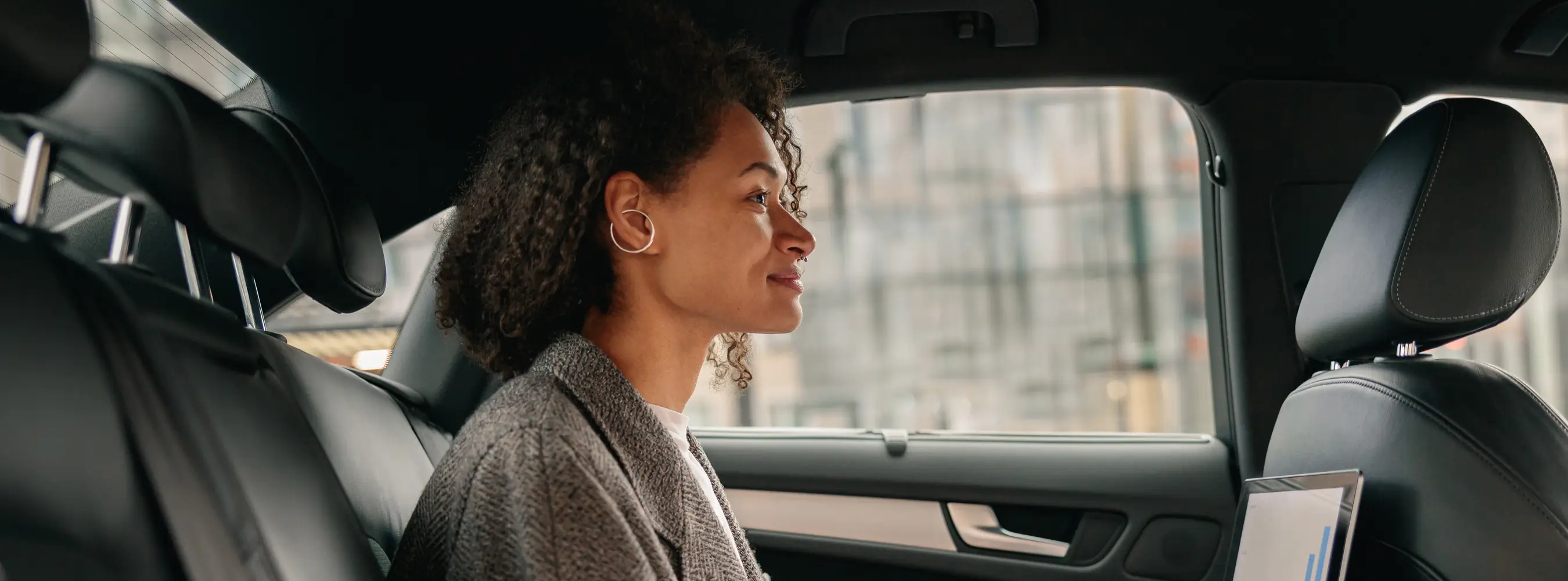 Employee looking out the window from the back seat of a car on the commute to work