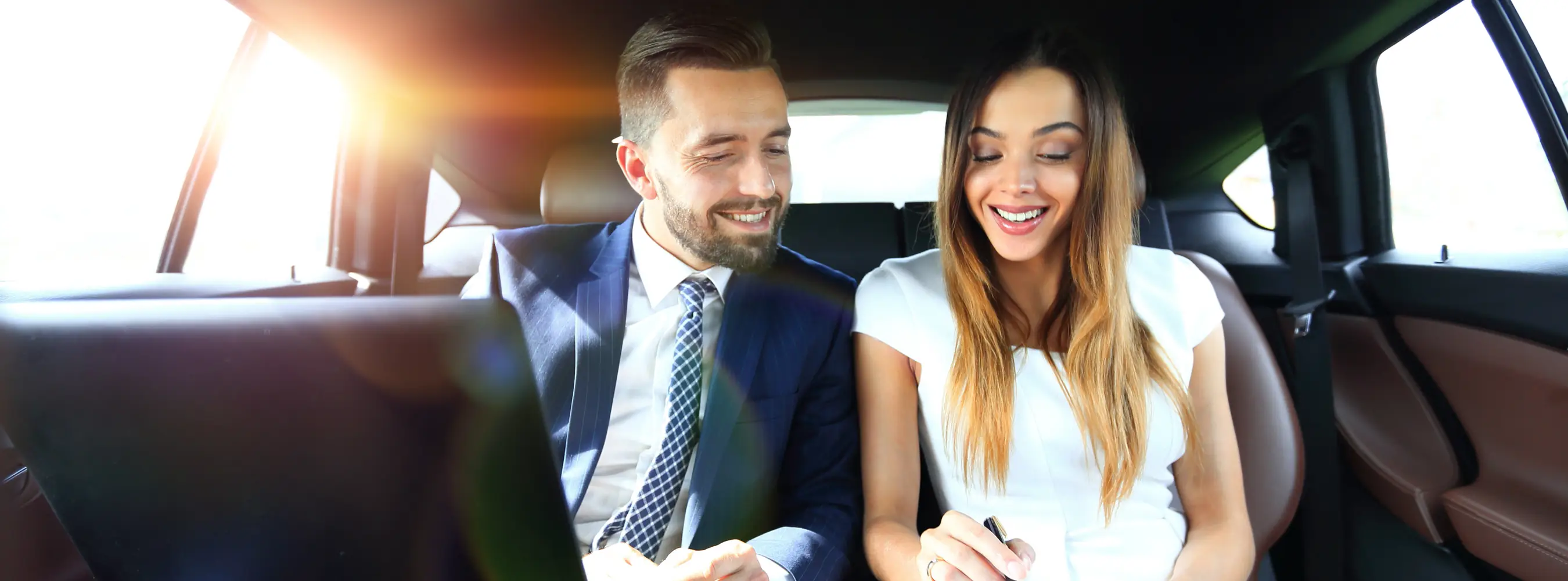 Two business colleagues working together in the back seat of a car