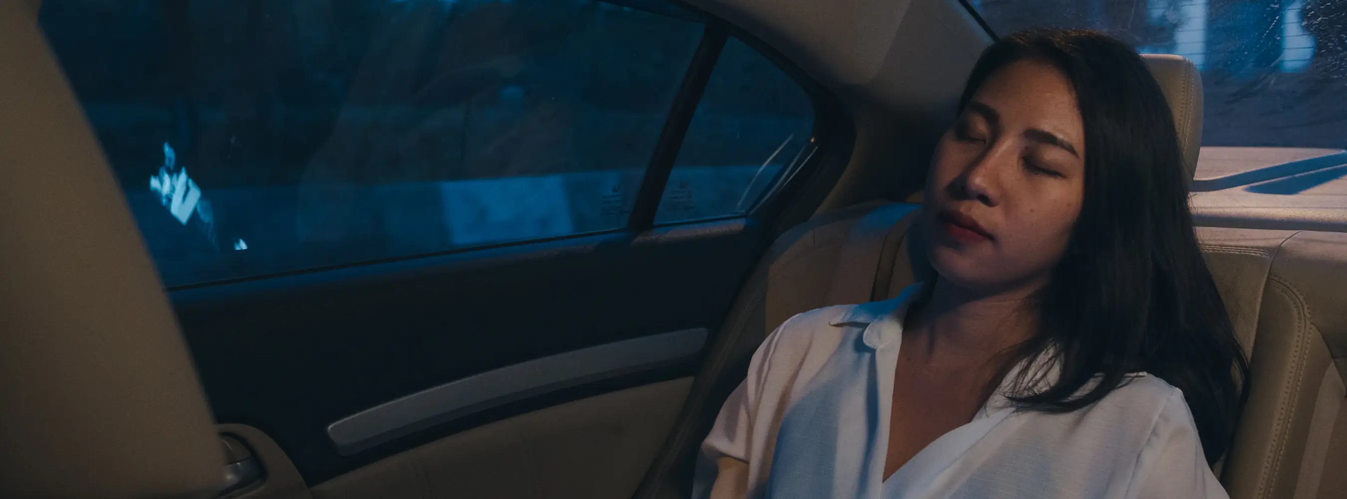 Staff member resting in the back seat of a car during a night-time journey