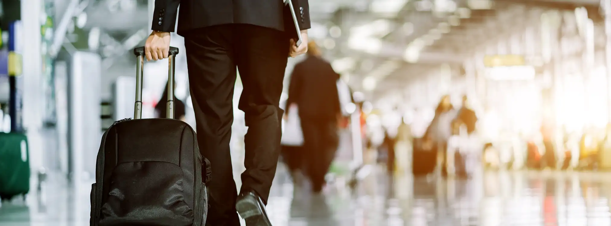 Businessman in a suit walking through an airport terminal with a suitcase