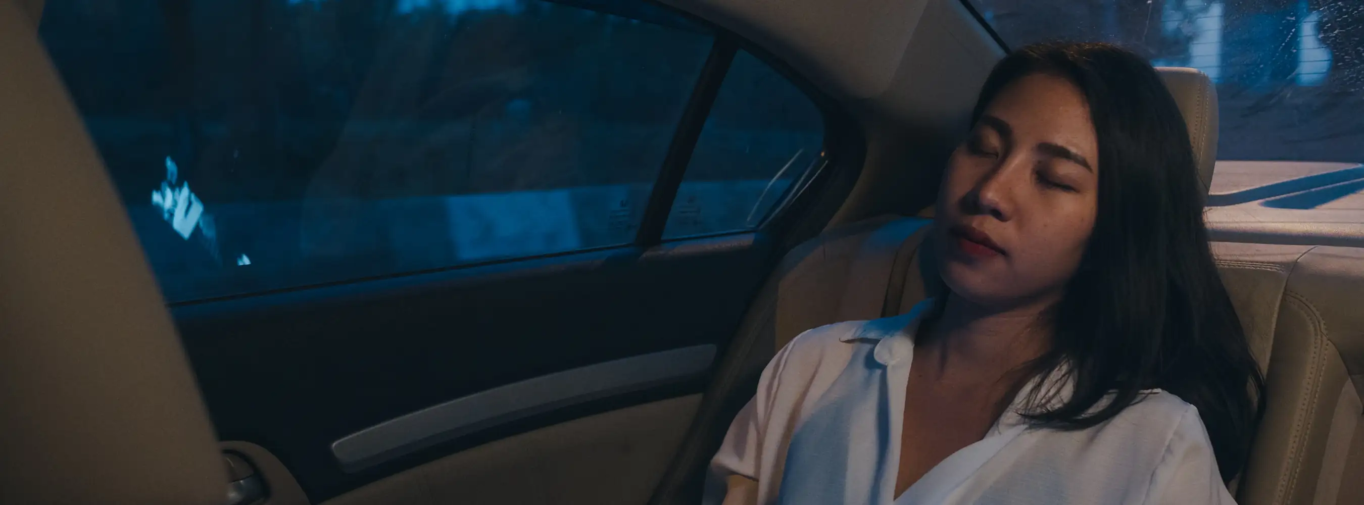 Staff member resting in the back seat of a car during a night-time journey
