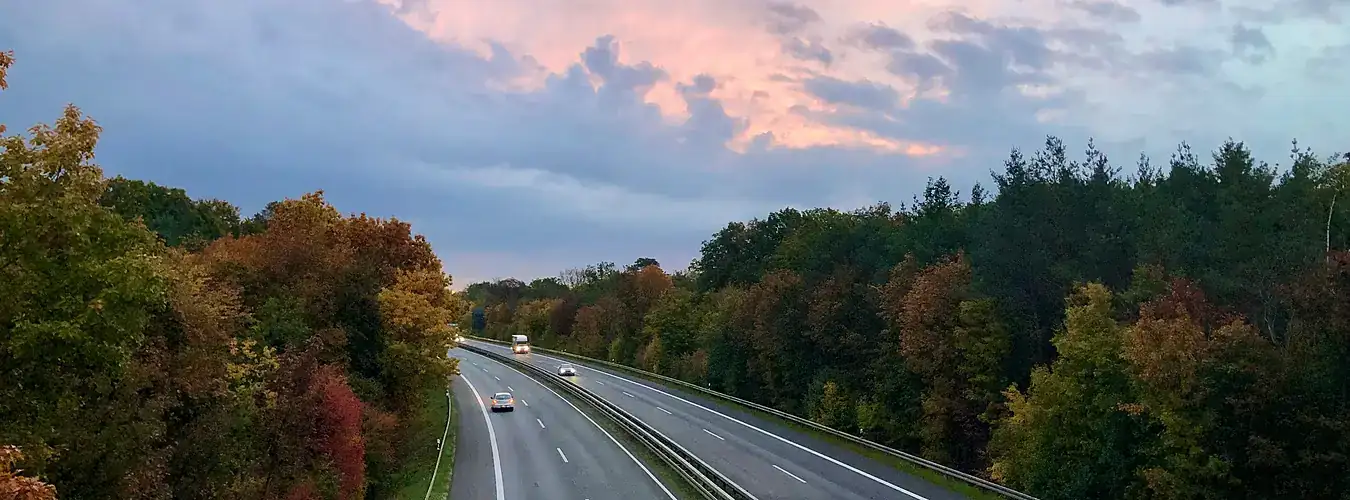 Cars on a motorway winding through autumn countryside at dusk