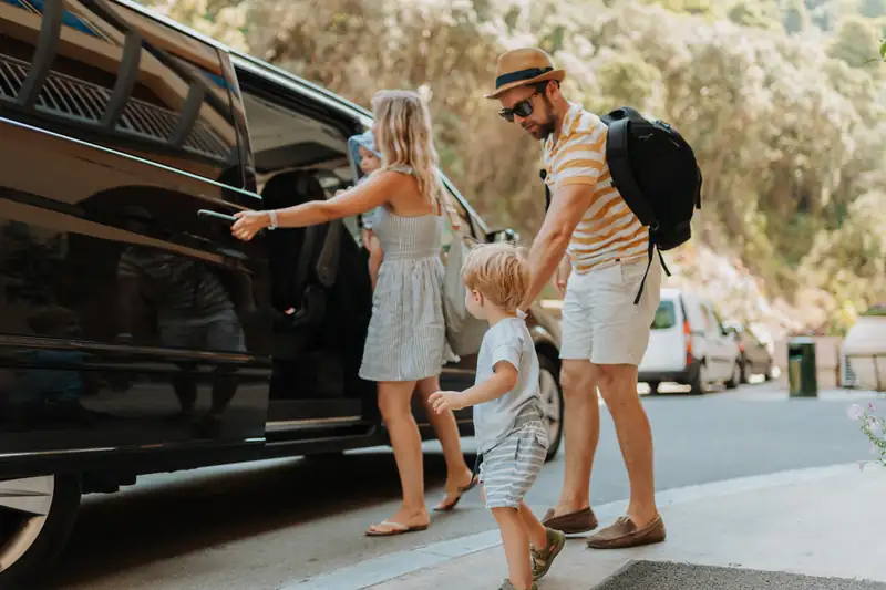 Family with luggage getting into a chauffeured van for a holiday transfer