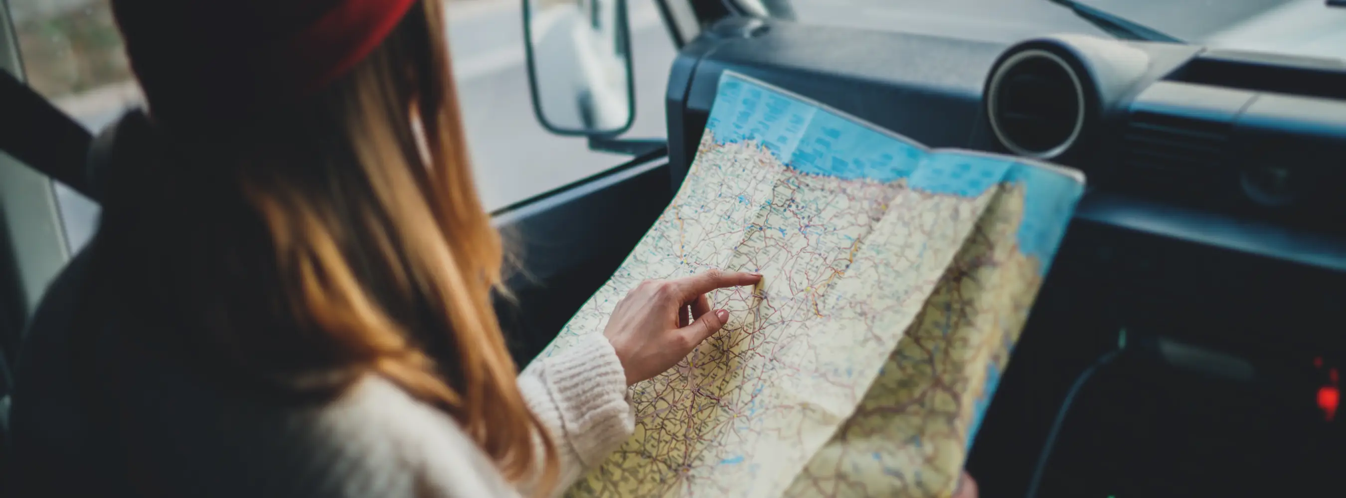 Passenger planning a route with a road map inside a van